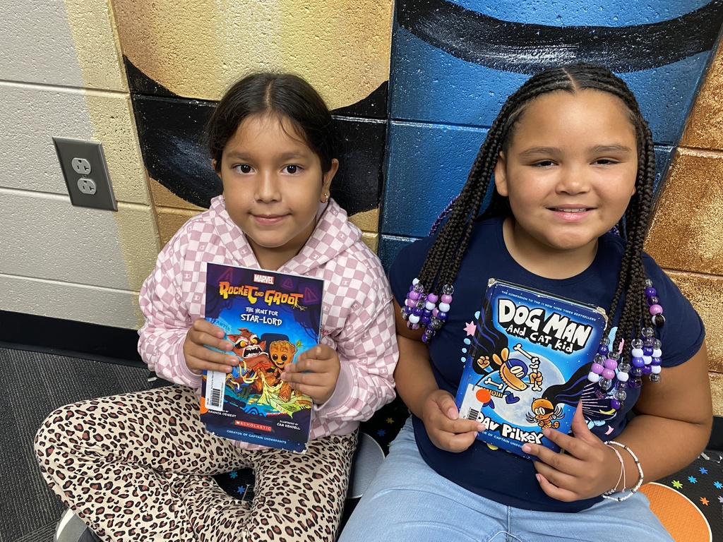 students holding their new library books up and smiling