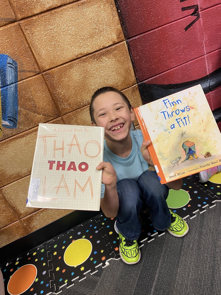 students holding their new library books up and smiling