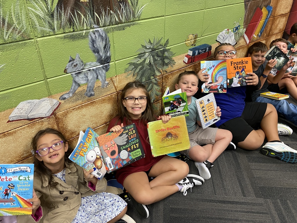 students holding their new library books up and smiling