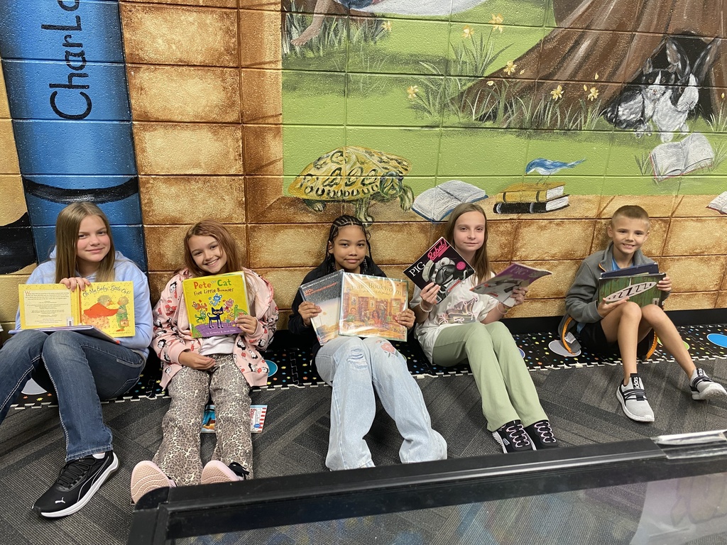 students holding their new library books up and smiling