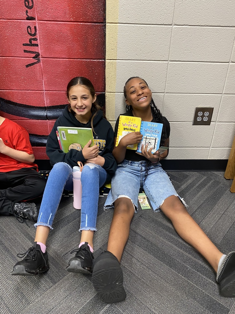 students holding their new library books up and smiling