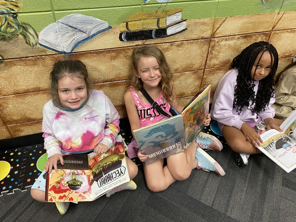 students holding their new library books up and smiling