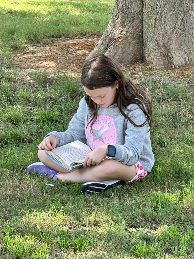 A pep student reading a book outside