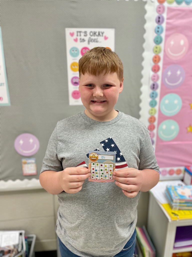 A student posing with his reading card filled up and completed.