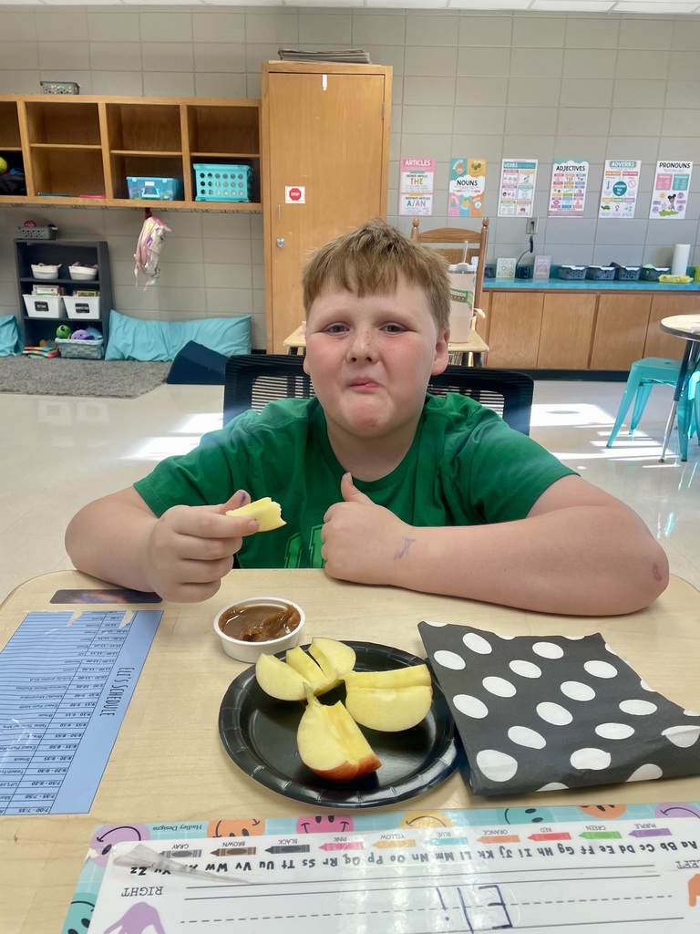 Today, Mrs. Willis' class devoured some delicious Honeycrisp Apples with caramel to go with an autumn science unit while watching a virtual field trip to an apple orchard. 🤎🍎 “I’m loving it!” ~Carson “These are tasty! ~Aurora “This is so good!” ~Eli “They’re good & sweet!” ~LayLay A student smiling with an apple in the picture.