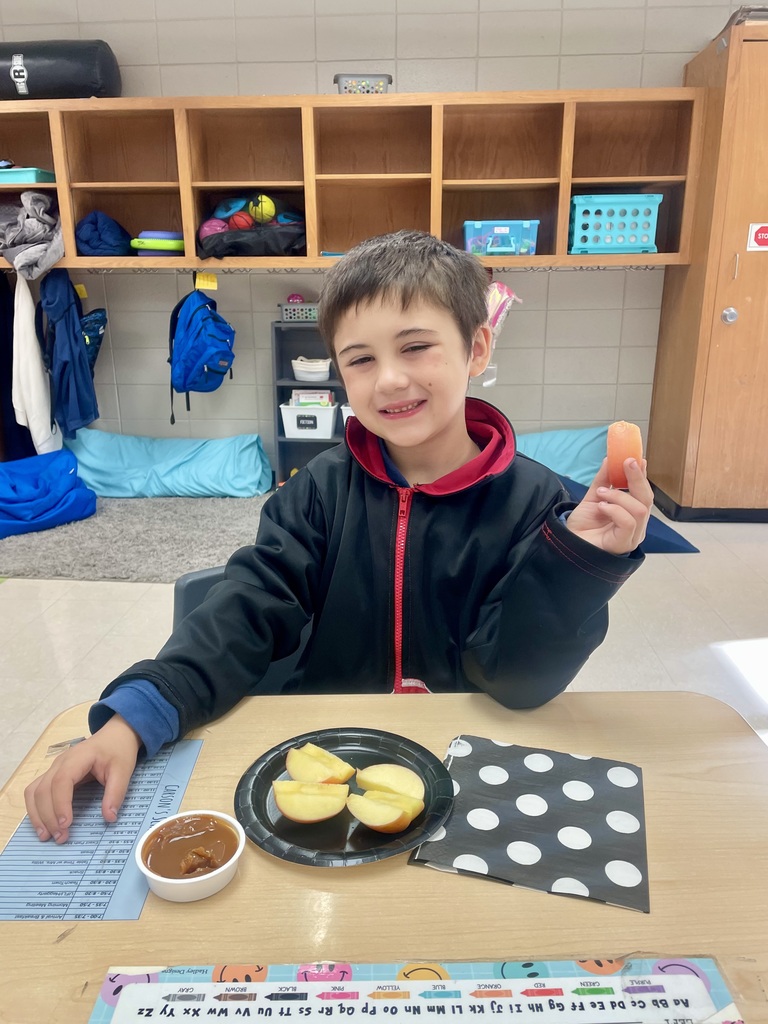 Today, Mrs. Willis' class devoured some delicious Honeycrisp Apples with caramel to go with an autumn science unit while watching a virtual field trip to an apple orchard. 🤎🍎 “I’m loving it!” ~Carson “These are tasty! ~Aurora “This is so good!” ~Eli “They’re good & sweet!” ~LayLay A student smiling with an apple in the picture.
