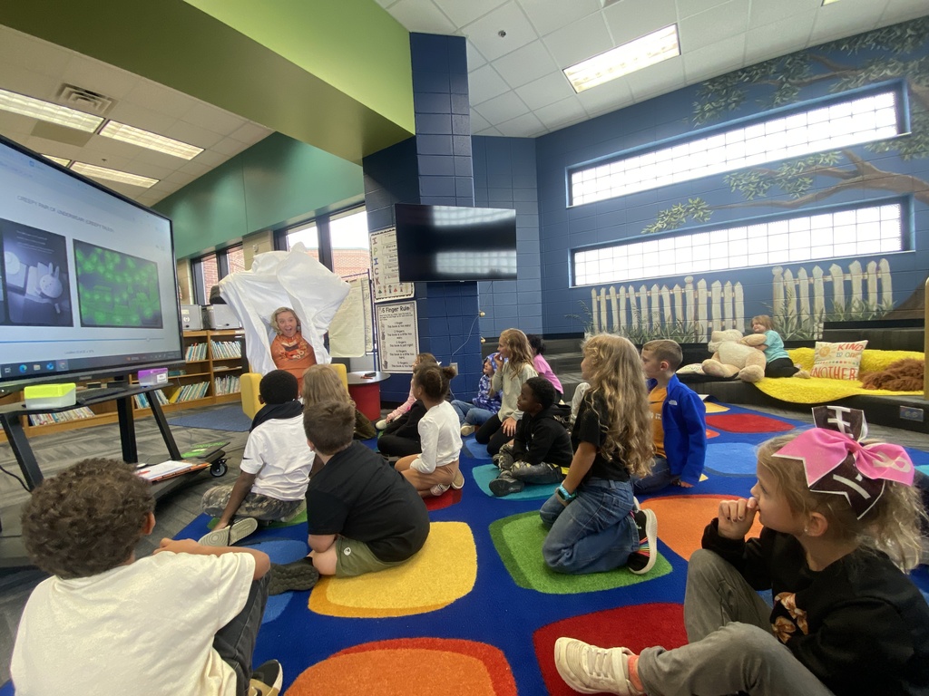 A parent reading a book as a mystery reader to Mrs. Chappell's class. 