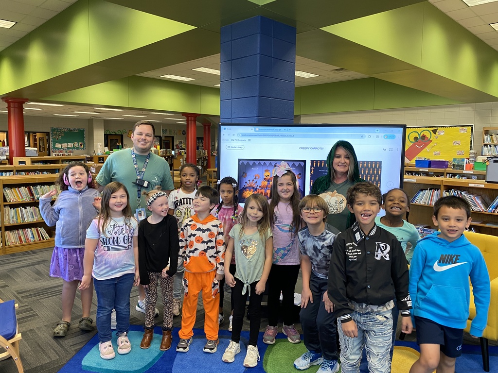 Mrs. Morris posing with  a book as a mystery reader with Mr. Bostwick's class. 