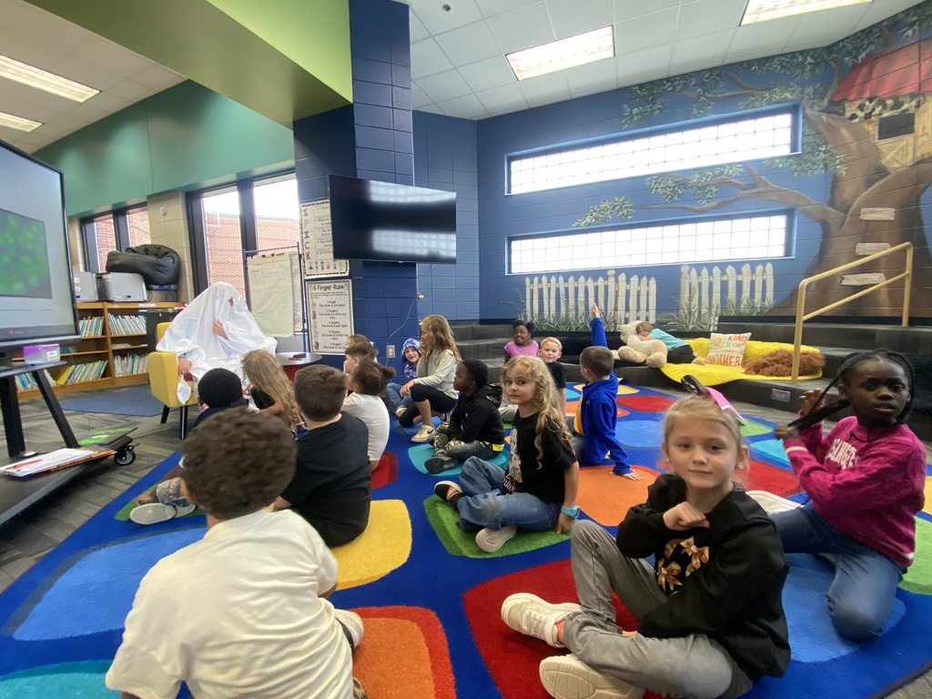 A parent reading a book as a mystery reader to Mrs. Chappell's class. 