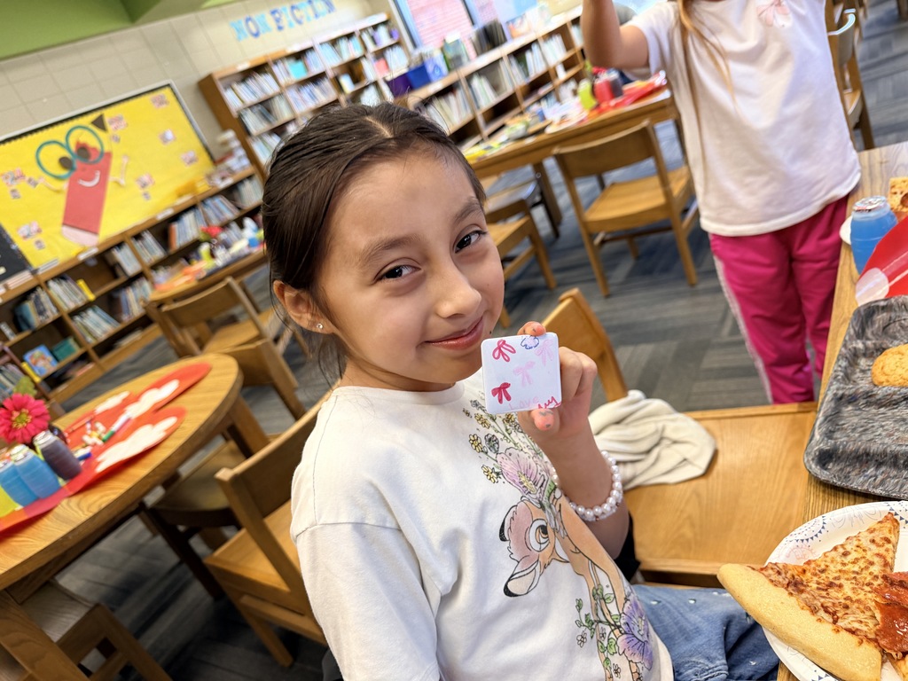 Kids smiling for a picture and eating pizza at the pizza party. 