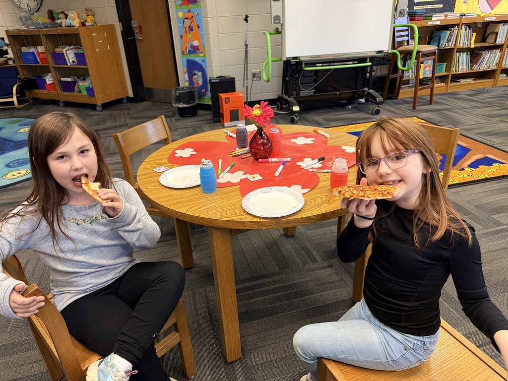 Kids smiling for a picture and eating pizza at the pizza party. 