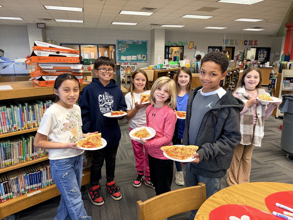Kids smiling for a picture and eating pizza at the pizza party. 