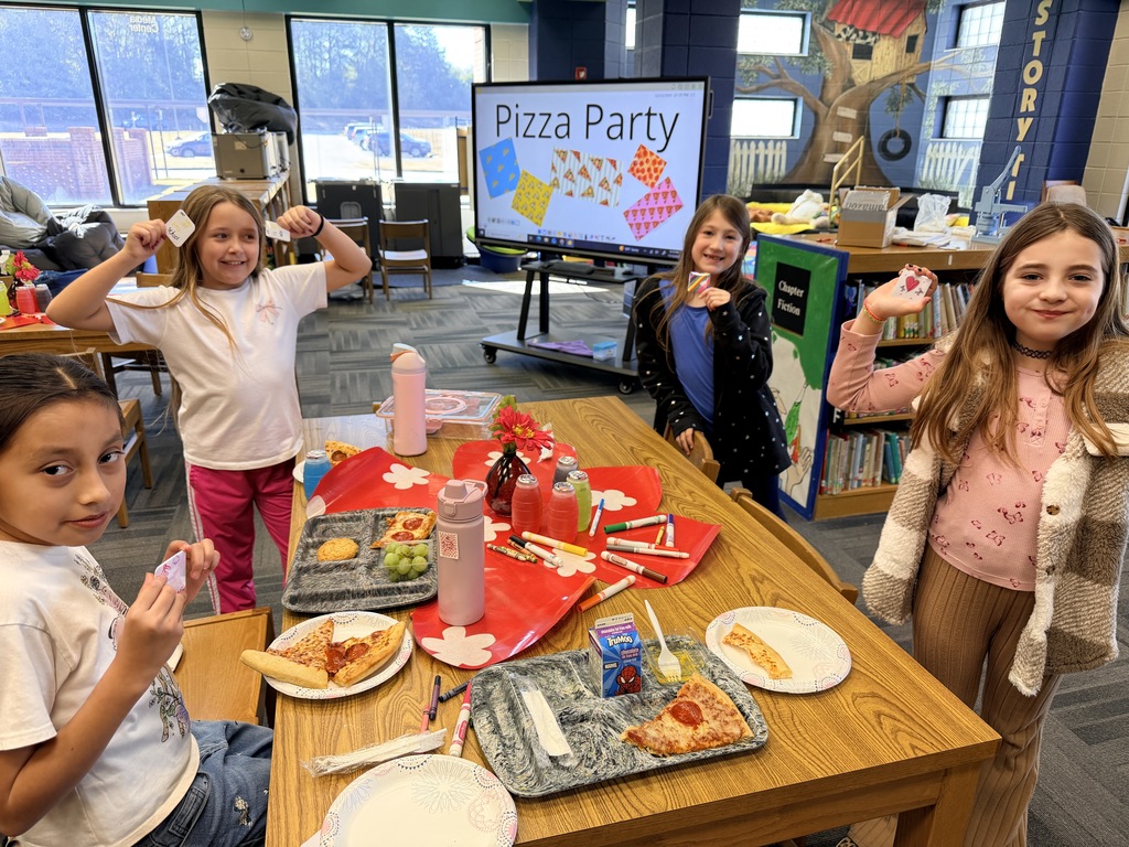 Kids smiling for a picture and eating pizza at the pizza party. 