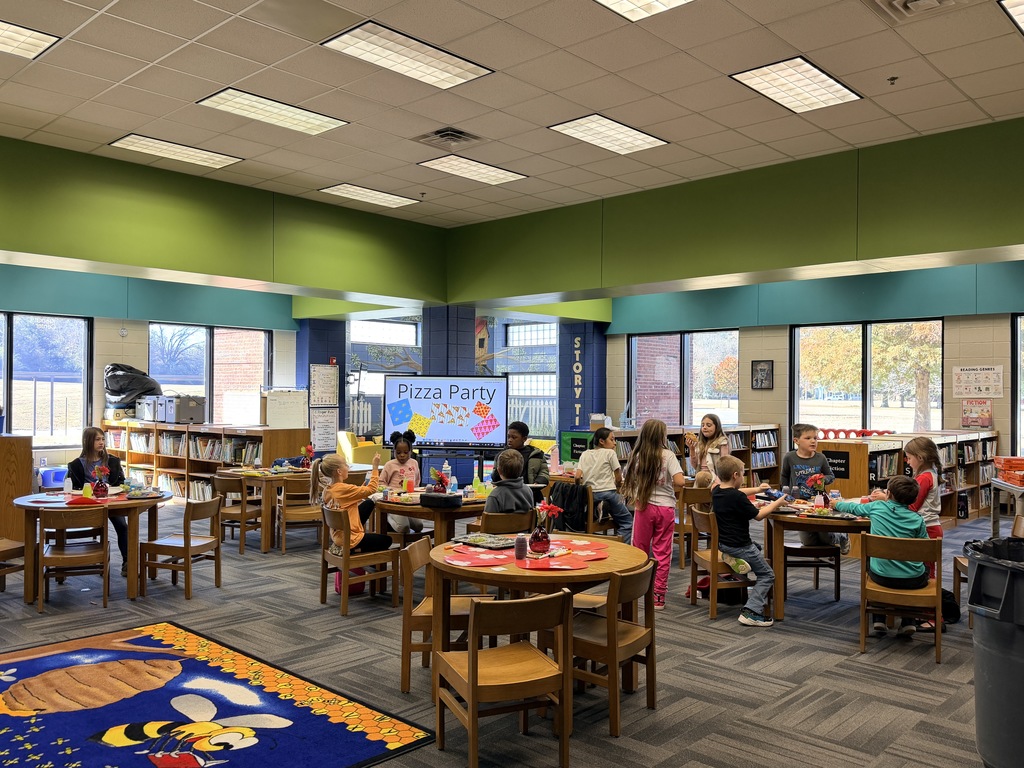 Kids smiling for a picture and eating pizza at the pizza party. 