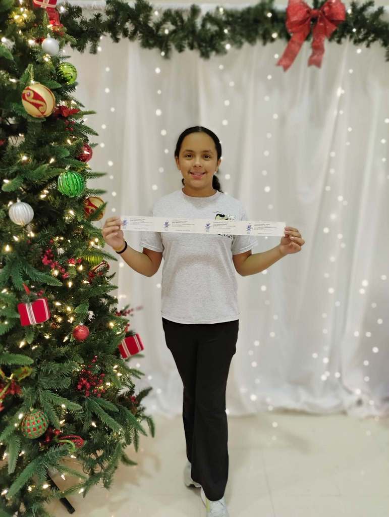 Ella Guzman won a prize at reading night. Her posing with her prize at the cute backdrop.