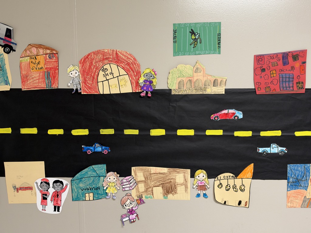 Image of a street with stores and cars drawn and colored by children