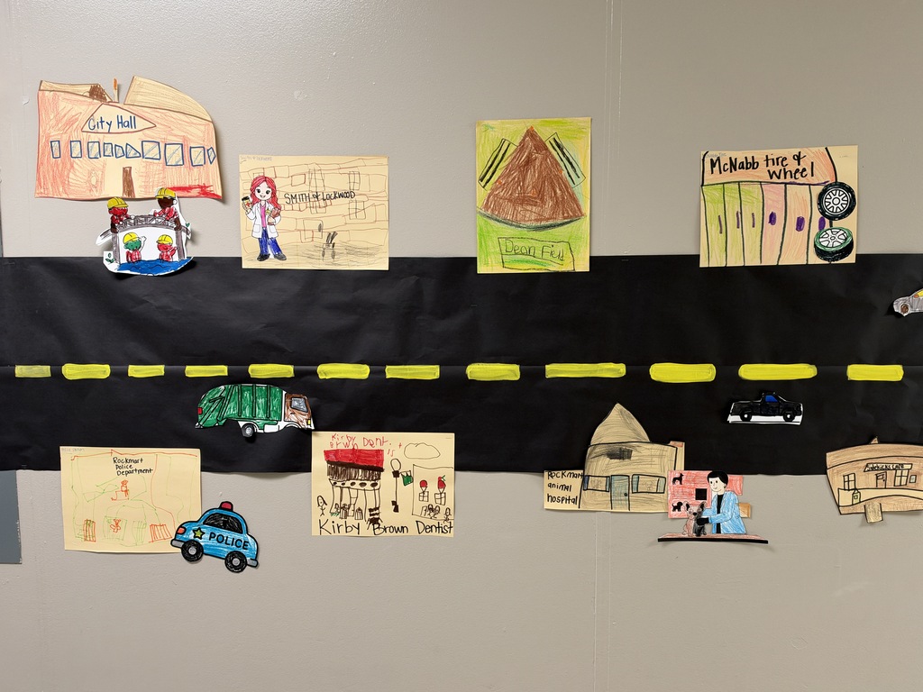 Image of a street with stores and cars drawn and colored by children