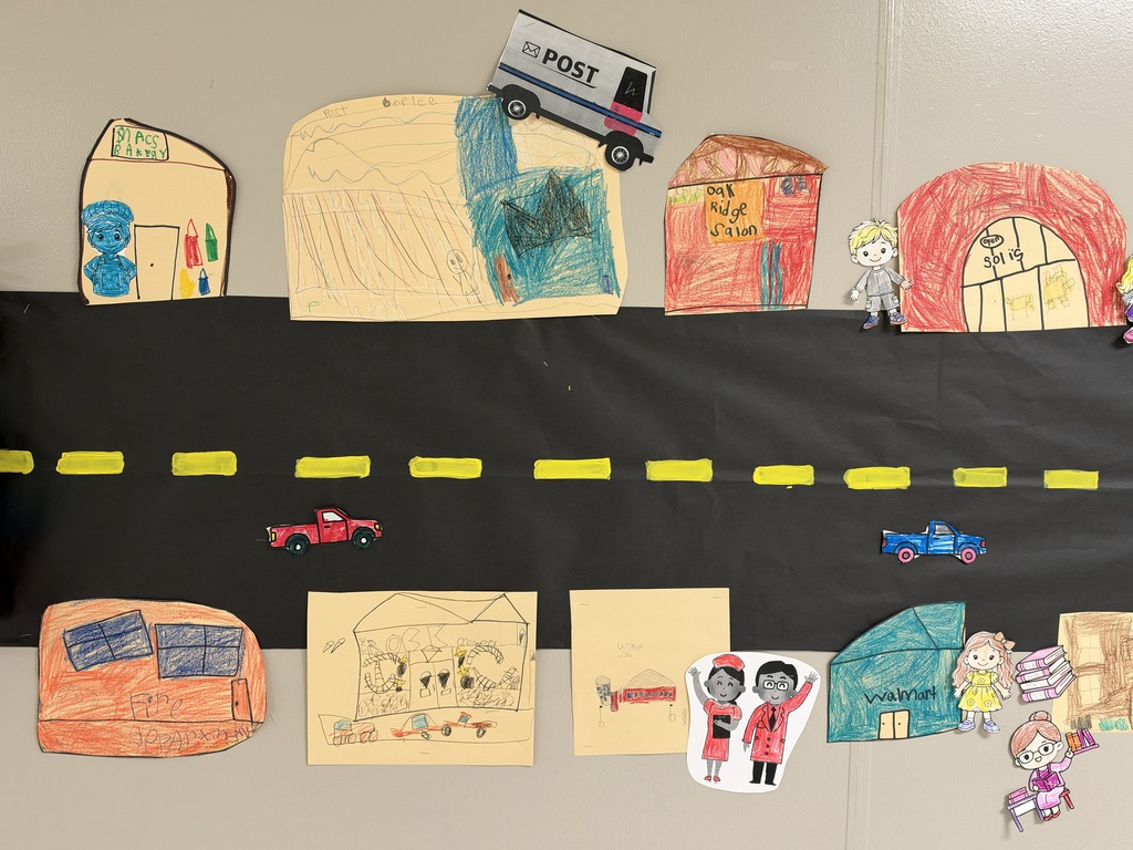 Image of a street with stores and cars drawn and colored by children