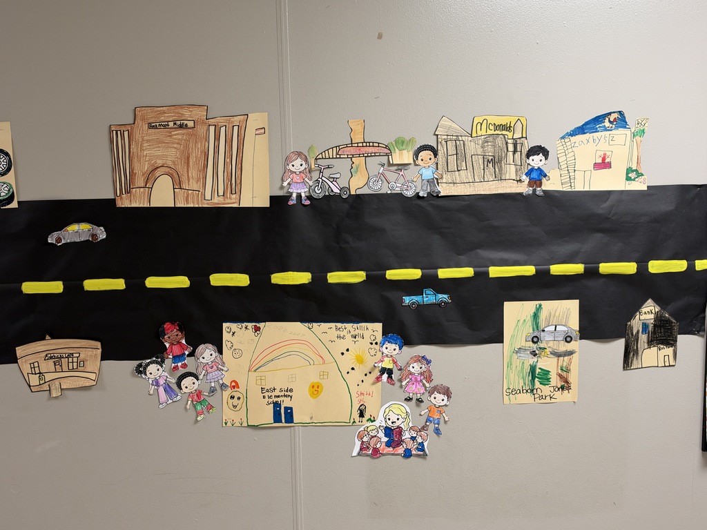 Image of a street with stores and cars drawn and colored by children