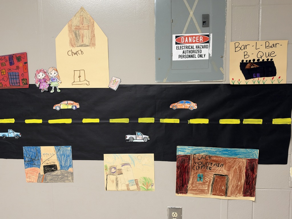 Image of a street with stores and cars drawn and colored by children