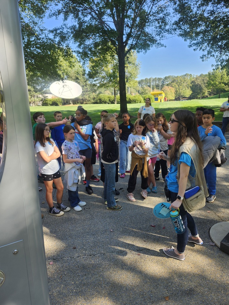 Picture of 4th grade students learning hands on activities on a field trip outside. 