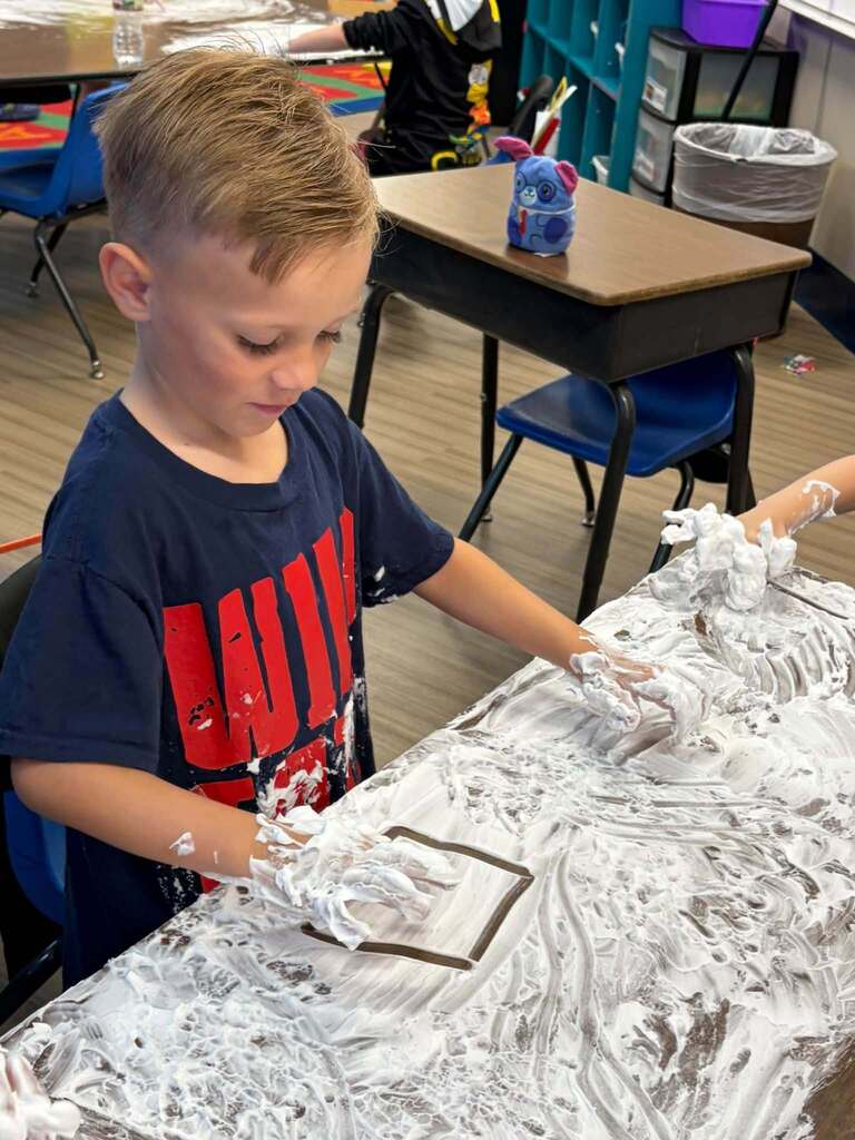 Child drawing square in shaving cream.