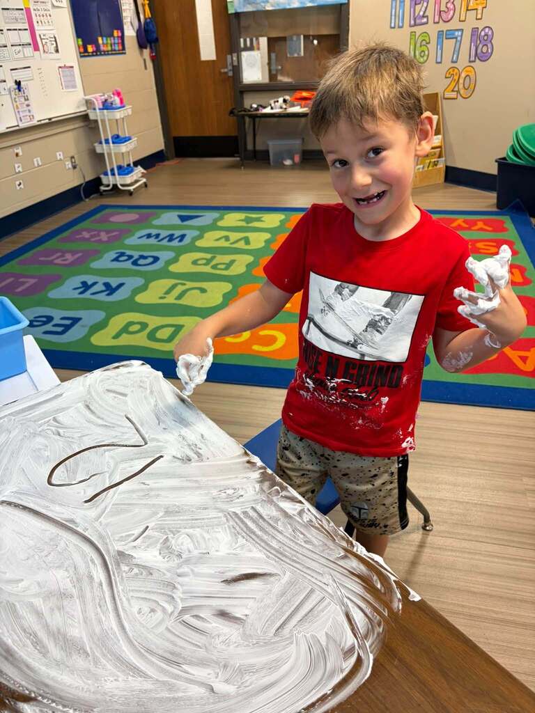 Child drawing numbers in shaving cream.