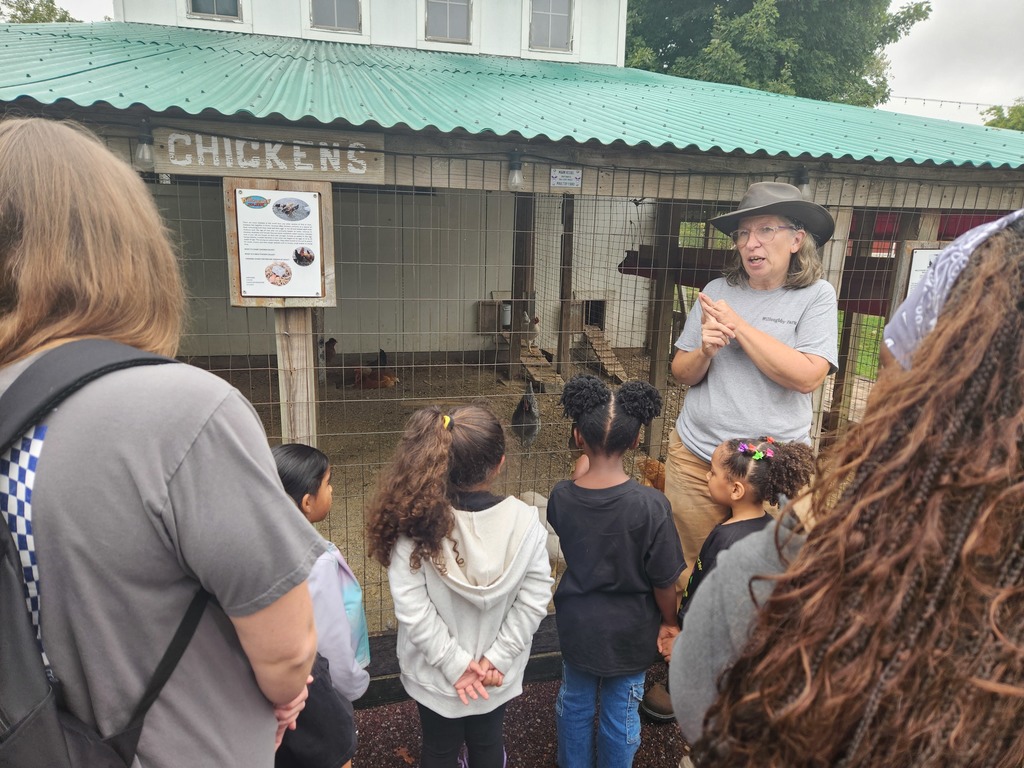 A tour guide talking to a group of students and parents outside a chicken coop