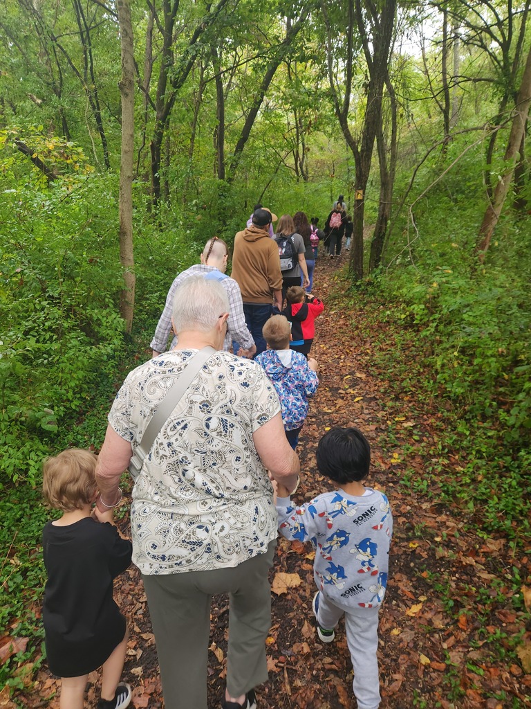A group of students and parents hiking a wooded trail