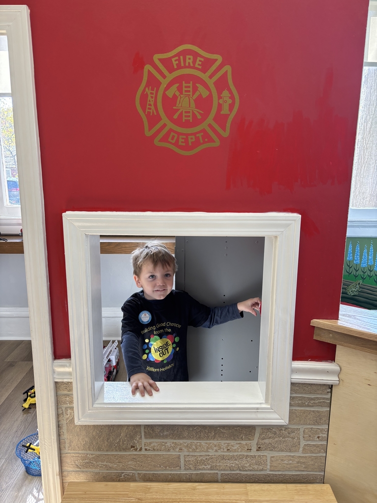 A boy in the window of a pretend fire department 