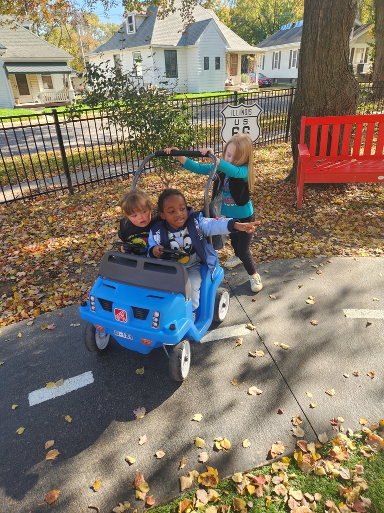 A girl pushes another girl and a boy in a toy car