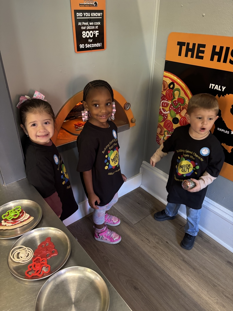Two girls and a boy stand in front of a pretend pizza oven