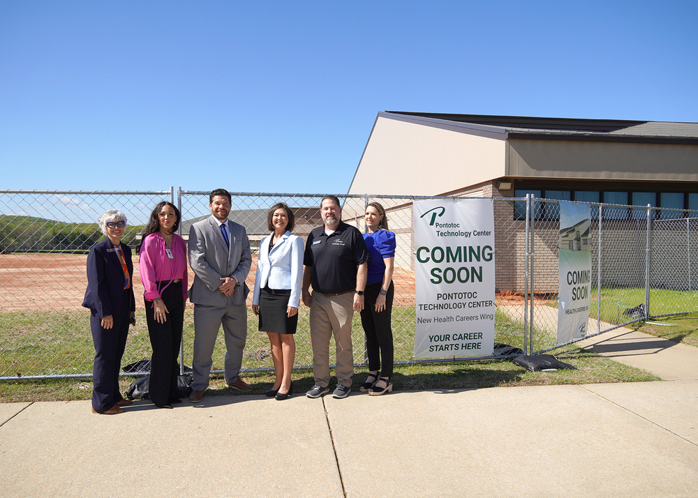 Group of people standing in front of a fenced off construction site