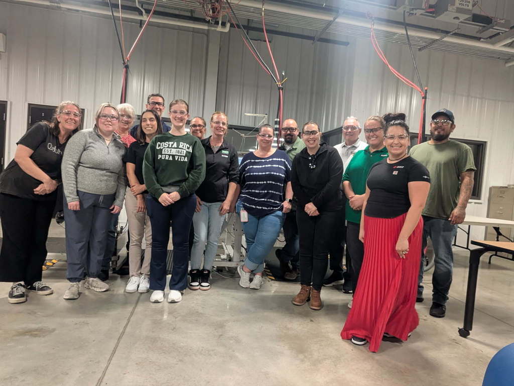 Group of people posing in front of industrial sewing machines