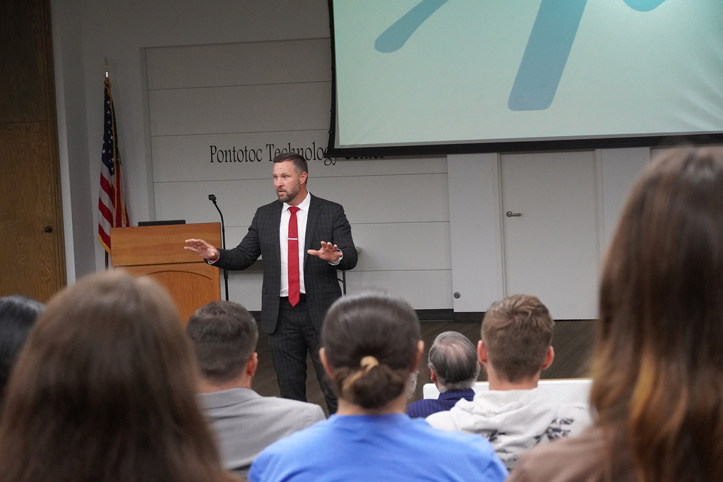 Man presenting to group in a seminar center.