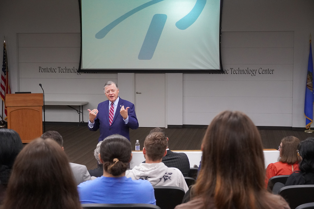 Man presenting to group in a seminar center.