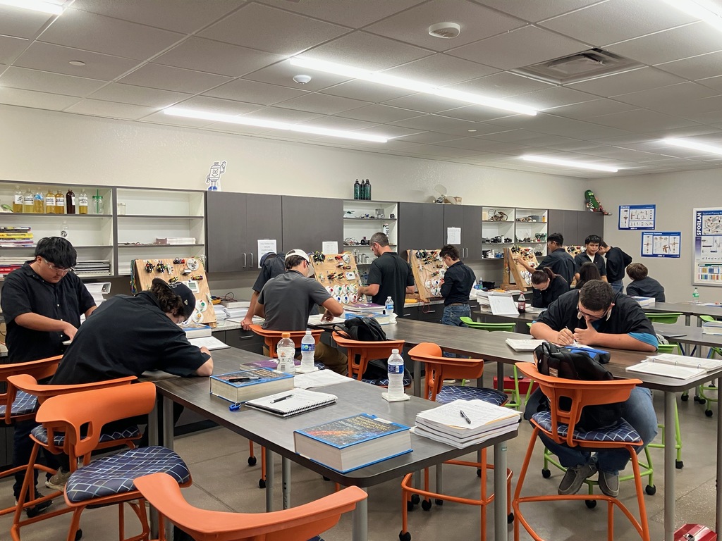 Students in a classroom working on electrical circuit boards.