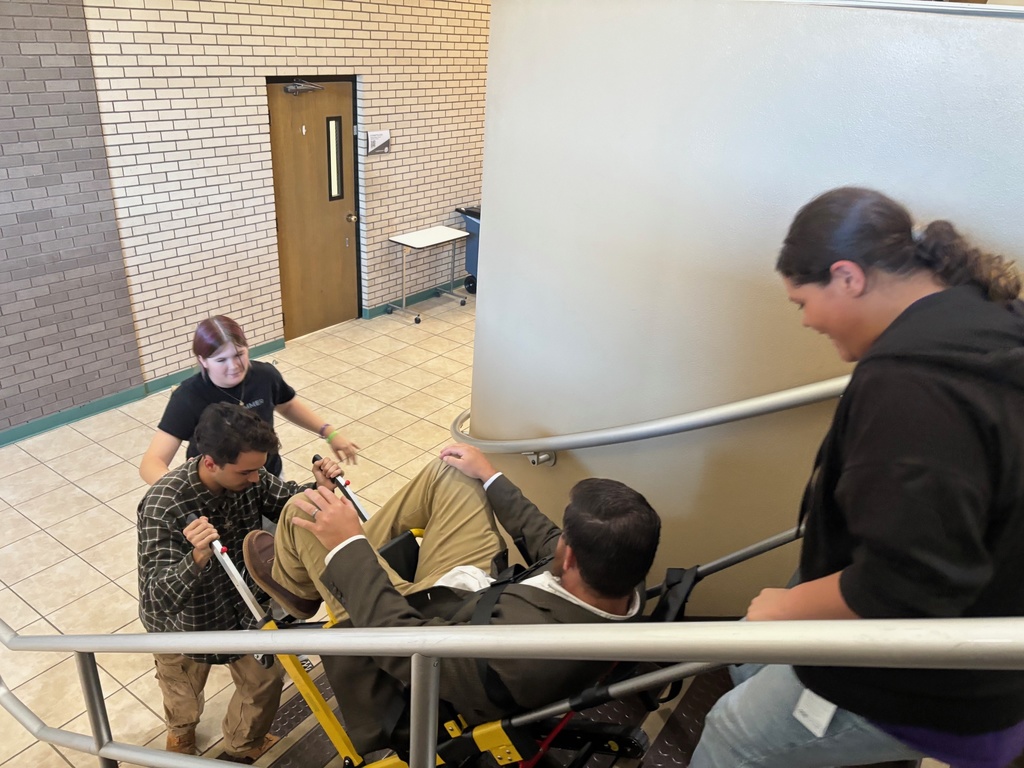 Students lifting a person up stairs in a transport chair 