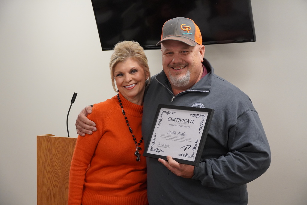 Two people posing with a framed certificate.