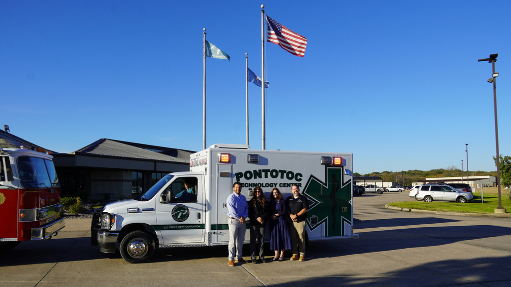 A group of four people posed in front of the ambulance