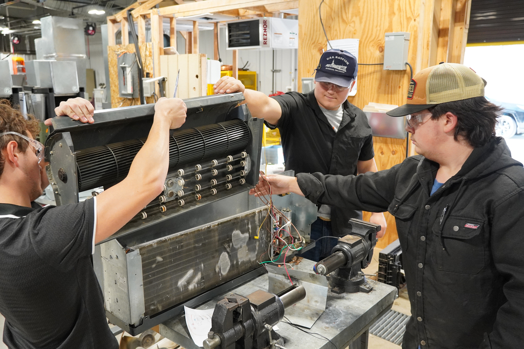 Students lifting a part out of an air conditioning