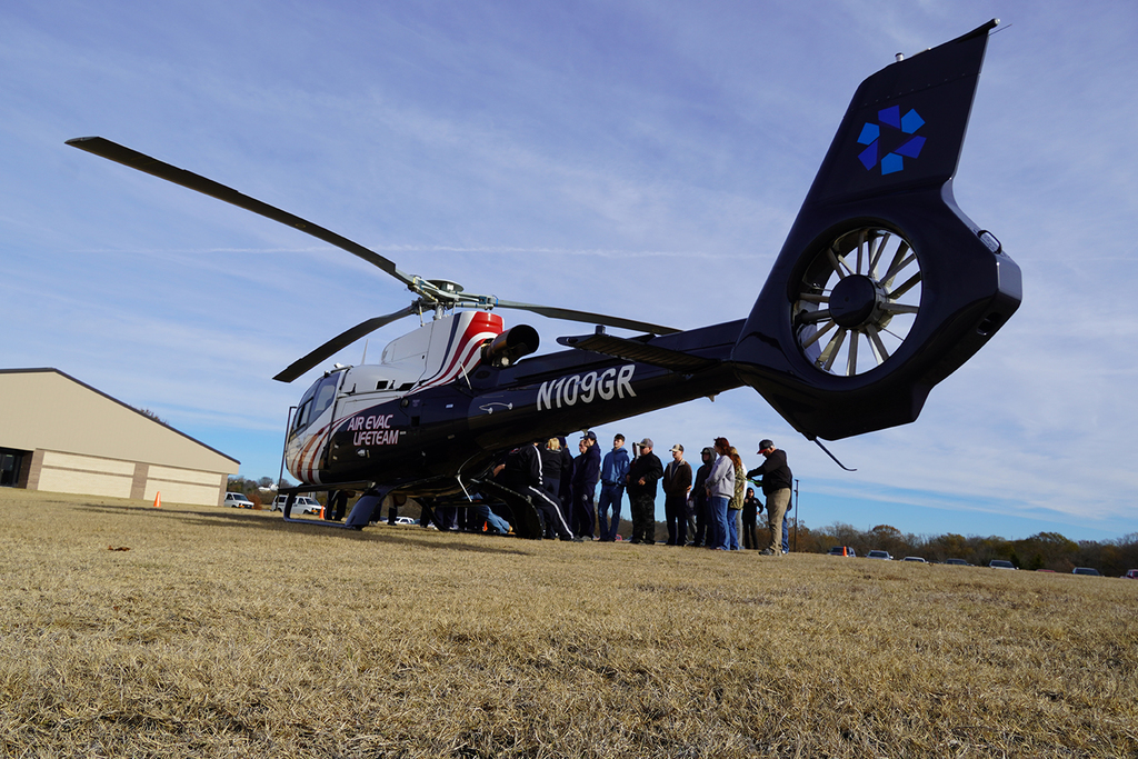 Helicopter in the foreground, students standing behind it in a group
