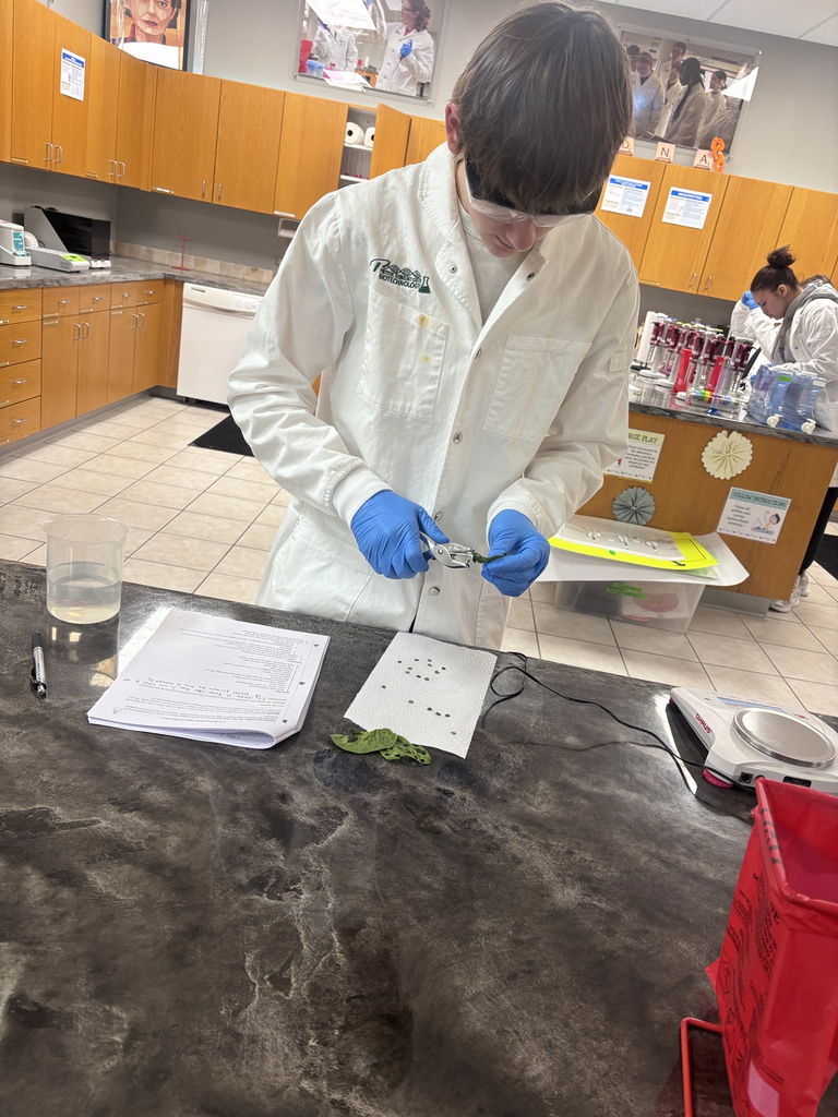 Student in white lab coat preparing a biotech experiment