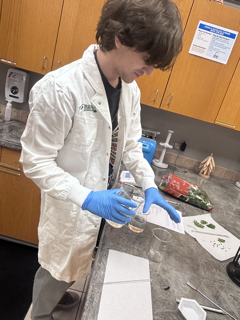Student in white lab coat preparing a biotech experiment