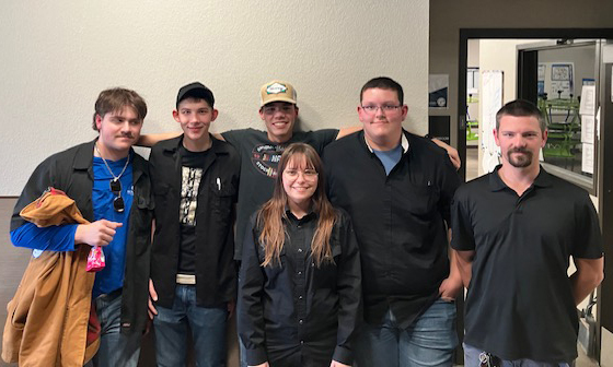 Group of people posing for a photo against a plain wall.