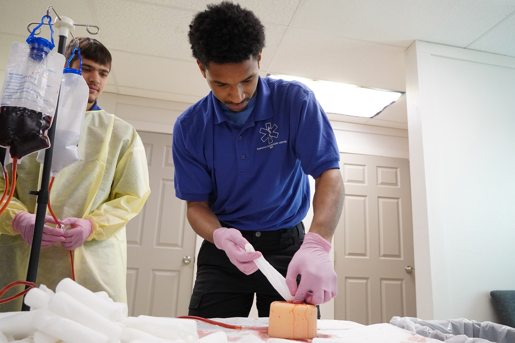 Two male students practicing stop the bleed techniques.