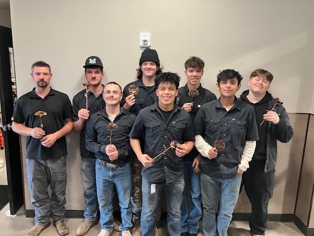 Group of people posing holding metal flowers
