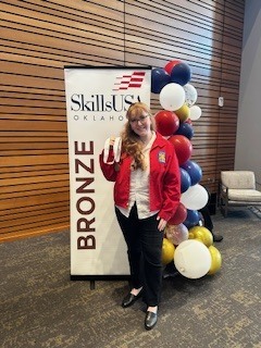 Photo of a female student in a red jacked holding her award medal.