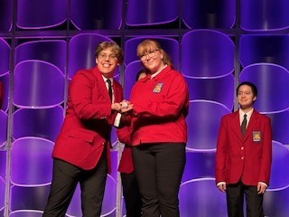 Photo of a female receiving an award on stage with a purple background.