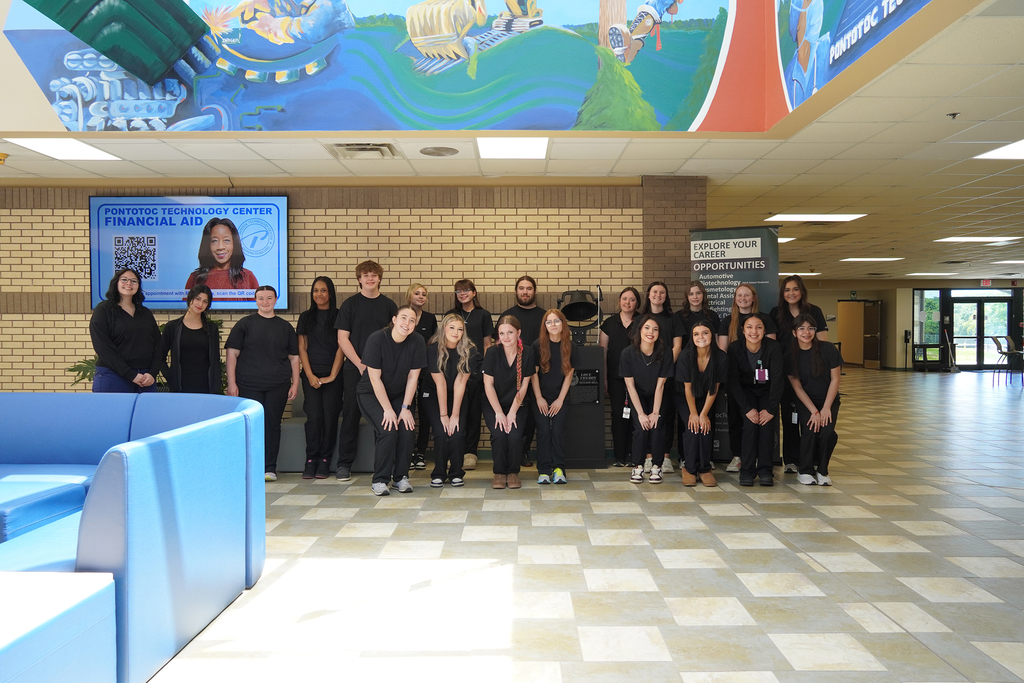 Large group of students posing  in front of the success bell.